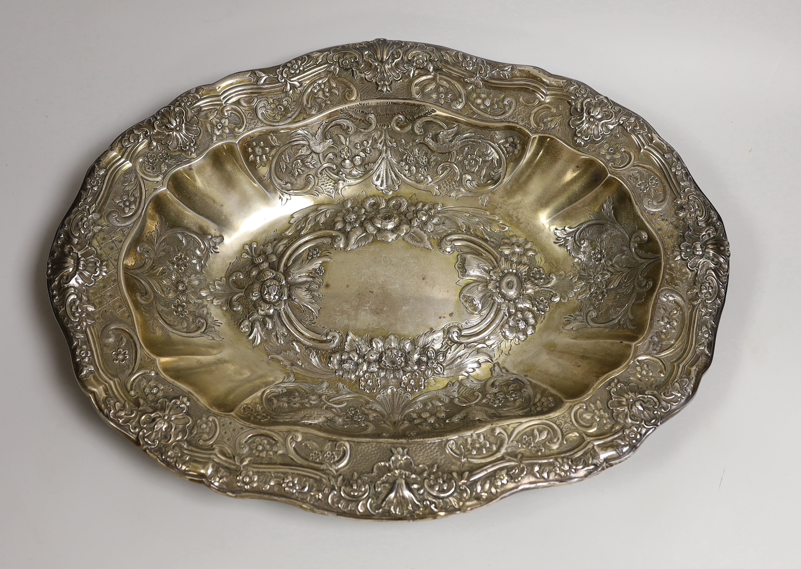 A large late 19th/early 20th century continental white metal oval bowl, embossed with birds, scrolls and flowers, 45.8cm, 40oz.